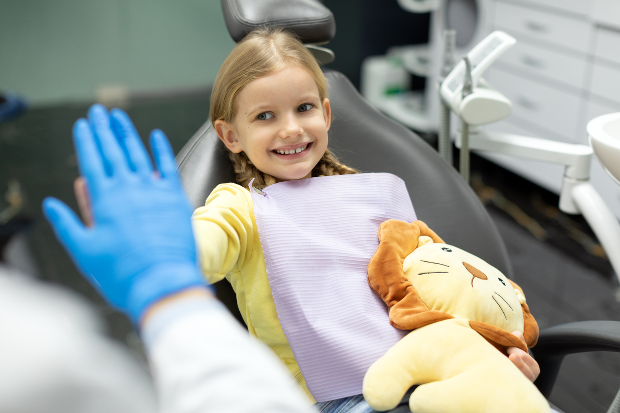 Smiling child enjoying a positive dental visit during summer preventive dental care appointment.