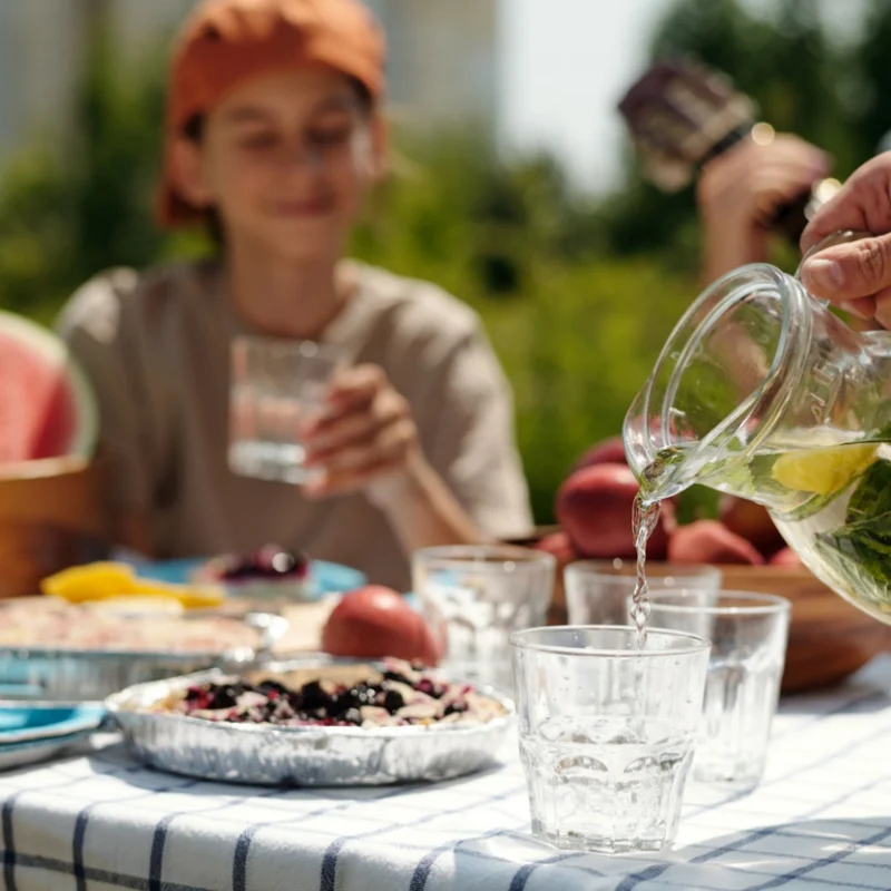 Family enjoying fruit-infused water and healthy foods outdoors during summer to support healthy dental habits for kids.