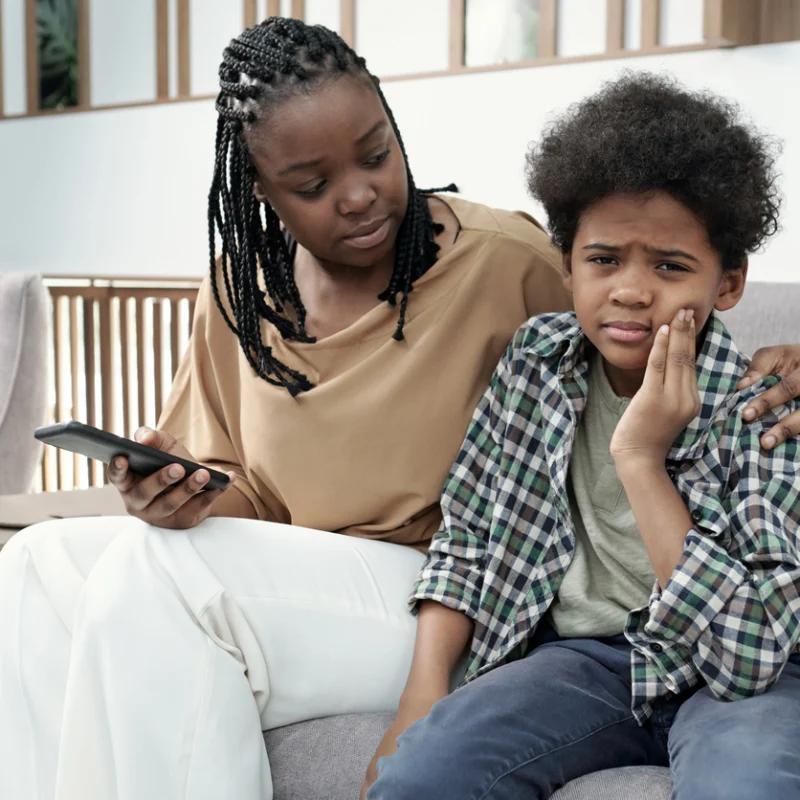Mother comforting her son with a toothache while seeking emergency pediatric dental care.